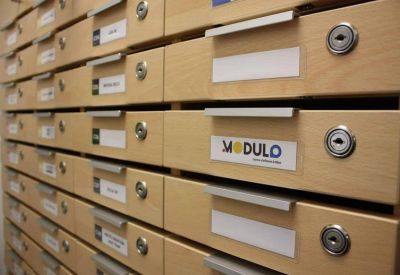 A wall of light wood mailboxes with individual locks and labels.