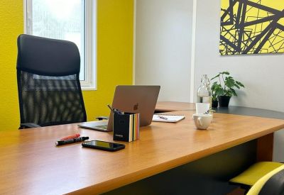 Professional workspace featuring a wooden desk, yellow accent wall, and geometric artwork.
