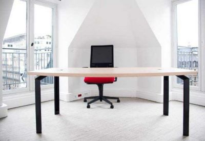 Private office featuring a minimalist desk and a red task chair set against an arched wall.