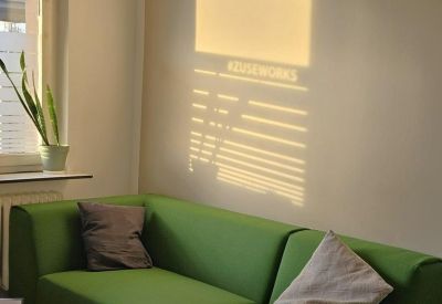 Modern green sofa against a wall featuring an artistic window light shadow.
