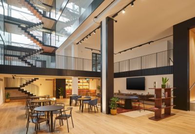 Large open atrium with wooden floors, black staircases, and various seating areas.