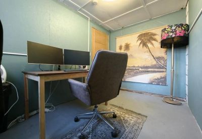 Quiet private office suite with dual monitors, a patterned lamp, and grey velvet chair.