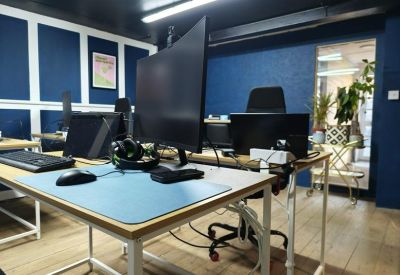 Multiple workstations with dual monitors and ergonomic chairs in a blue-themed office.