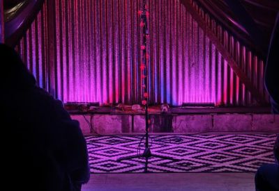Performance space with purple accent lighting, a microphone stand, and geometric rug.