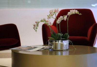 Close-up of a lounge area featuring plush red velvet armchairs and an orchid.