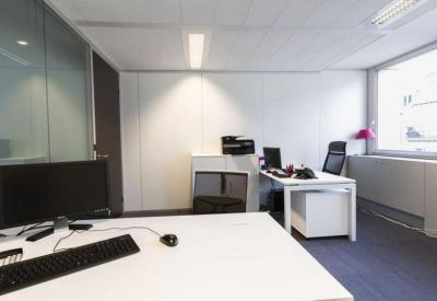 Bright private office suite with white desks and glass partitions.