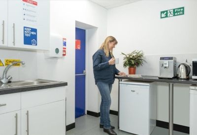 Communal kitchen area featuring white cabinetry, a coffee machine, and a small dining counter.