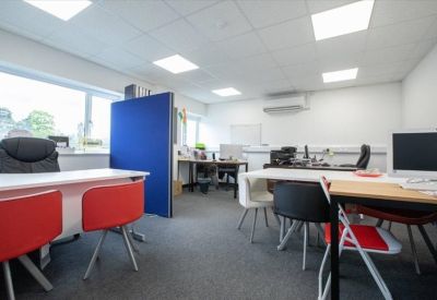 Bright open-plan office space with white desks, red chairs, and blue privacy screens.
