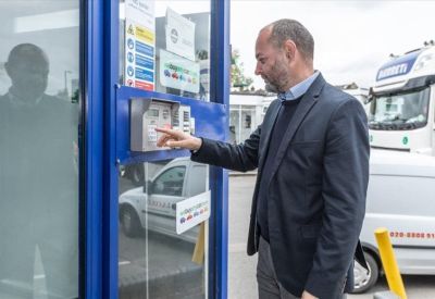 Man using a keypad entry system at a blue secure entrance point.