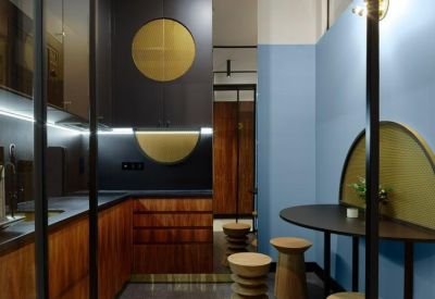 Office kitchen and break area with wood cabinetry, blue walls, and stylish wooden stools.