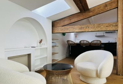 Cozy lounge area with curved white armchairs and exposed timber beams.
