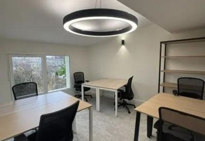 Bright workspace with a large circular pendant light and shared desks.
