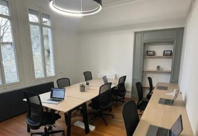 Meeting room with a central wooden table, black chairs, and a feature bookshelf.