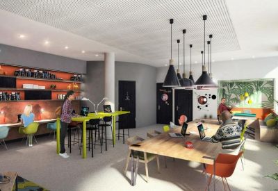 Vibrant coworking office with long wooden tables, yellow accents, and industrial-style lighting.