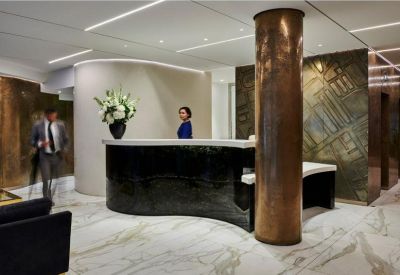 Chic reception area with a curved black desk, marble floors, and copper pillar.