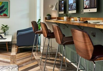 Modern coworking space featuring a wooden bar height desk and high-back stools.