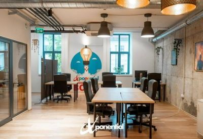 Sunlit communal room with a large lightbulb mural and industrial ceiling pipes.