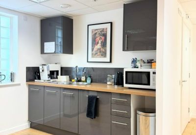 Modern kitchenette with grey cabinetry, wooden countertops, and a built-in microwave.