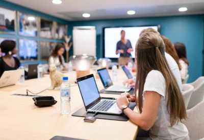 Modern conference room with team members working on laptops at a long light-wood table.