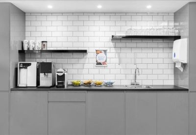 Modern kitchen and tea point area with grey cabinetry and white subway tile backsplash.