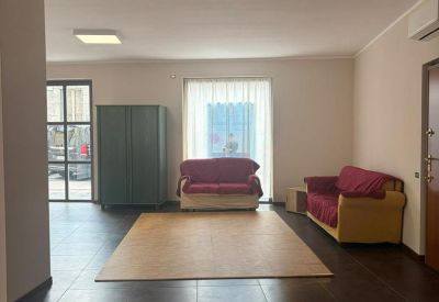 Large lounge area with two red sofas, a light wood rug, and a dark green wardrobe unit.