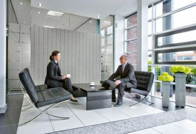Contemporary breakout lounge with black leather chairs and bright green floral accents.