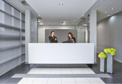 Modern white reception desk with staff and vibrant yellow flower arrangements.