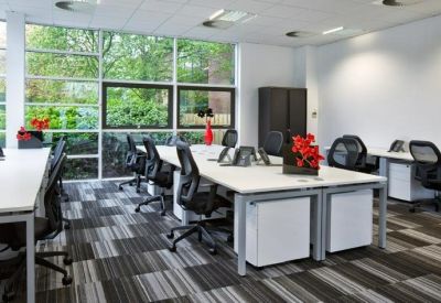 Spacious open-plan office area with large windows and multiple ergonomic workstations.