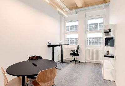 Modern meeting room with a black oval table, wooden chairs, and a height-adjustable desk.