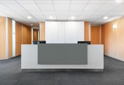 Bright reception desk with a white and grey facade and wood-paneled walls.