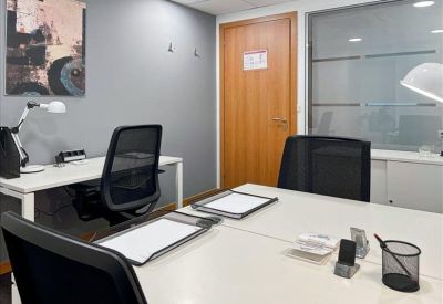 Modern kitchenette area with white high-top stools and a coffee machine.