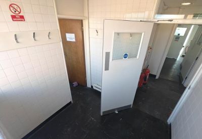 Changing area or cloakroom with wall-mounted hooks and white tiled walls.