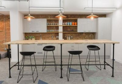 Modern communal kitchen and breakout area with a long high table and industrial bar stools.