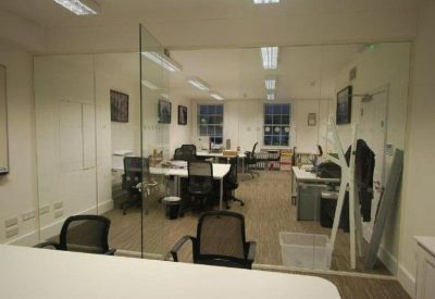 Bright office space with multiple workstations and glass partitions.