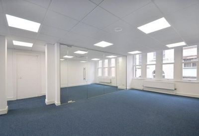 Spacious, bright open-plan office suite with blue carpeting and large mirrors.