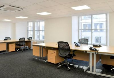 Modern office suite featuring several wooden desks with ergonomic chairs.