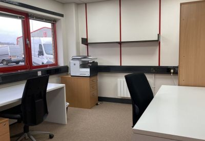 Bright private office featuring white desks, black ergonomic chairs, and red window frames.