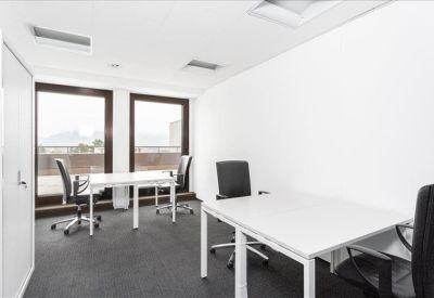 Bright private office featuring two white desks and large windows.