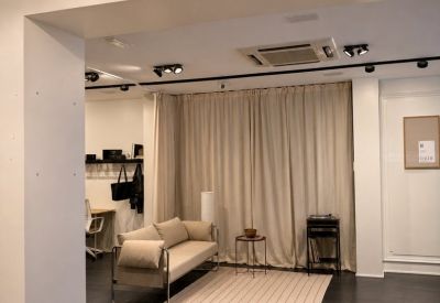Communal lounge area with a sleek sofa, striped rug, and warm overhead spotlights.