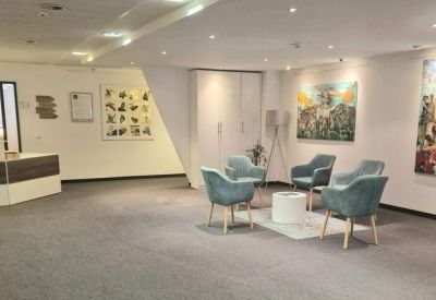 Bright reception and waiting area with light blue chairs and contemporary artwork.