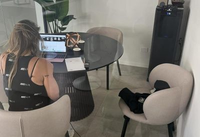 Glass-enclosed private workspace with a circular table and modern scoop chairs.