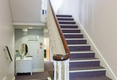 Purple carpeted hallway and stairs leading to a bright white reception area.