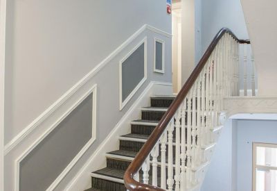 Grand staircase with white banisters and decorative wall panels.