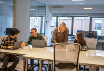 Bright coworking space with a team working around a large white table with laptops.