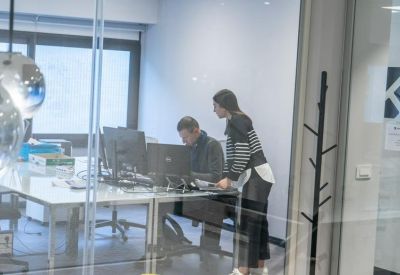Glass-walled office space where two people are collaborating at a desk.