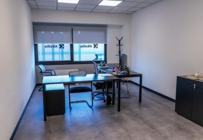 Private office suite featuring a dark wooden desk and ergonomic chairs.