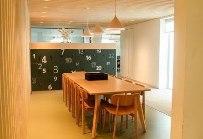 Warm breakout space featuring a long wooden table and a chalkboard wall with numbered graphics.
