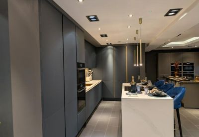 Modern communal kitchen with dark grey cabinetry and a white marble island with blue bar stools.