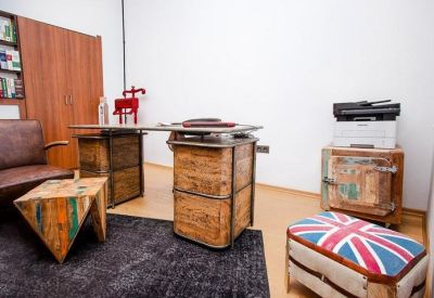 Eclectic private office featuring a rustic wood desk and a Union Jack patterned ottoman.