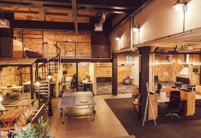Industrial loft coworking space with a ping pong table and spiral staircase.